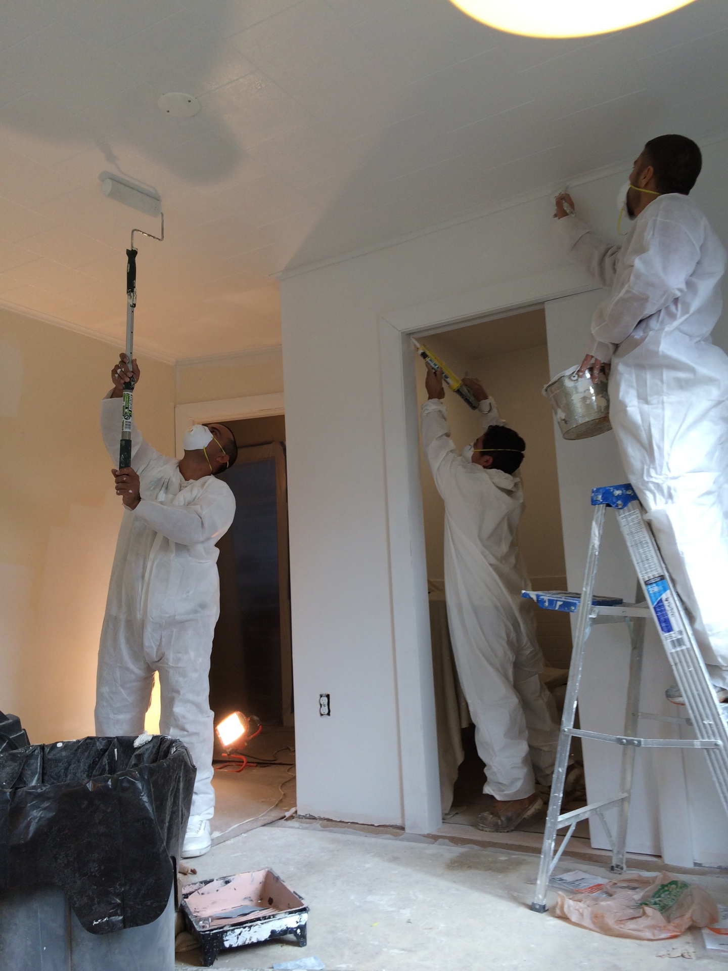 Painter sanding and caulking baseboard trim before paint